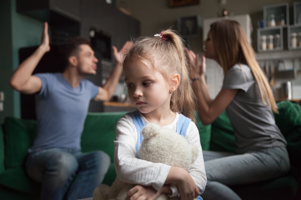 Kid daughter feeling upset while parents fighting at background
